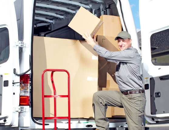 photo of a happy mover loading cart items into moving van